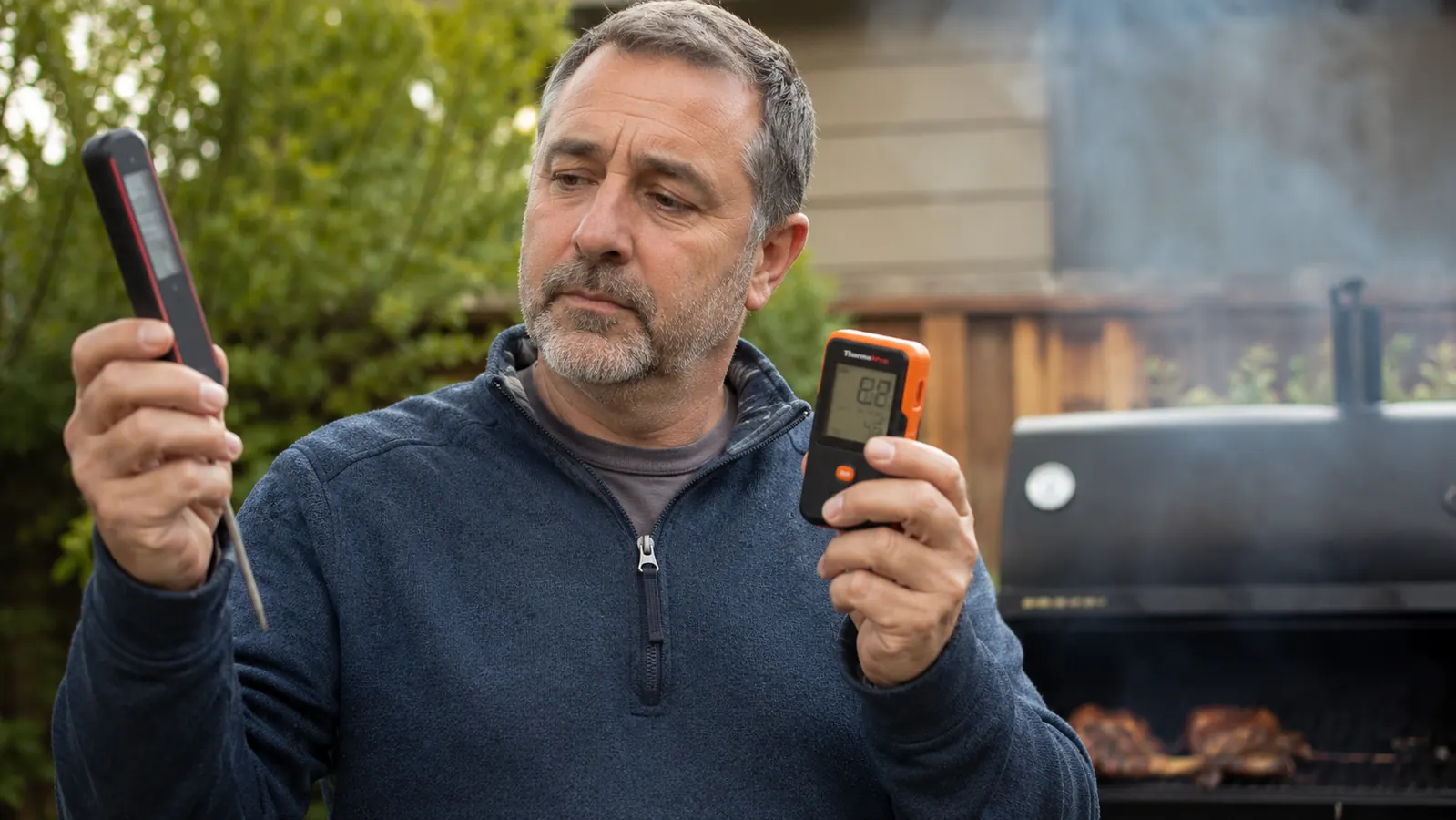 MEATER wireless probe inserted in a whole chicken on a covered kettle grill while the cook watches a phone app showing temperature over time
